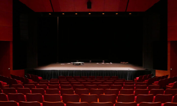 1701397-3b5aed58-empty-stage-with-few-props-red-seats.jpg